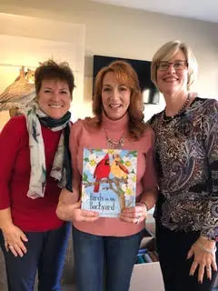Author holding the book with a woman on either side